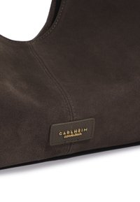 Bolso de ante marrón oscuro con un diseño de corte curvado. Presenta una etiqueta estampada en dorado con "Carlheim Copenhag" y finos acentos de costura.