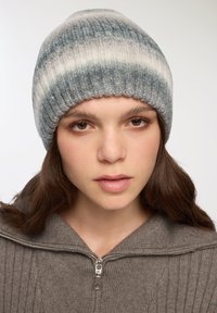 Berretto lavorato a maglia in tonalità di grigio e blu con righe orizzontali, caratterizzato da una texture a coste e un materiale morbido e caldo.