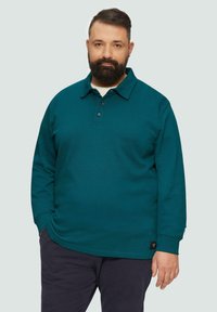 Türkisfarbenes Langarm-Polohemd mit Knopfleistene, Kragen und strukturiertem Stoff. Schwarzes Markenetikett sichtbar am Saum.