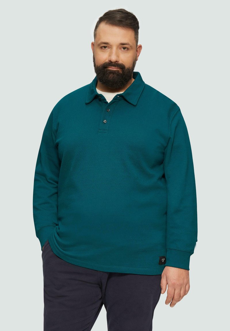 Türkisfarbenes Langarm-Polohemd mit Knopfleistene, Kragen und strukturiertem Stoff. Schwarzes Markenetikett sichtbar am Saum.