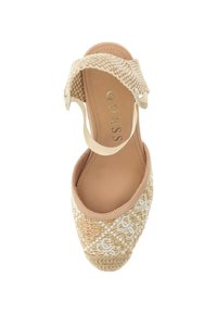 Sandalia de cuña beige con textura trenzada y patrón floral. Presenta una correa trenzada y una plantilla suave de color claro con la marca.