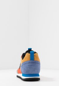 Flerfärgad sportskor med överdel i mocka i orange, gult och blått. Har en svart nät-tunga och en blå hältab.