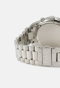 Silver stainless steel watch with a segmented bracelet and round case. Includes two pushers and a crown on one side; blank case back.