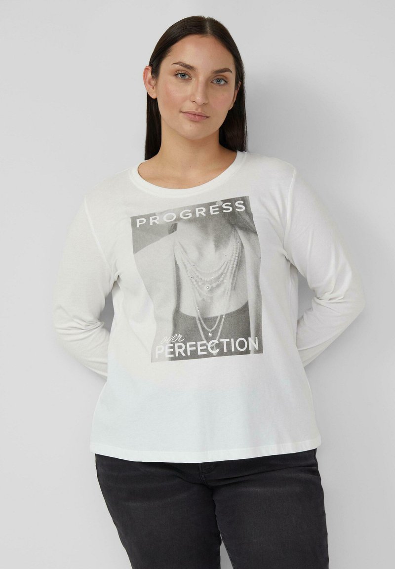 Witte T-shirt met lange mouwen met een zwart-wit grafische print en de tekst "VOORTGANG boven PERFECTIE." Zacht katoenen materiaal.