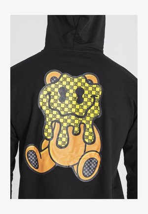 Felpa nera con cappuccio caratterizzata da una grande grafica di un orso cartone con un motivo giallo e nero, design che gocciola e accenti arancioni.