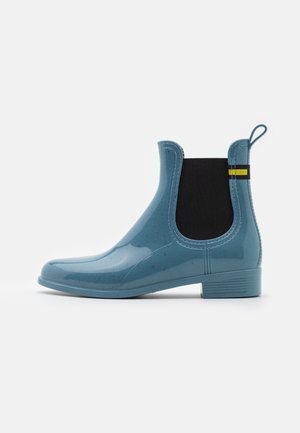 Bottes de cheville en caoutchouc bleu avec finition brillante, panneaux latéraux élastiques et languette de traction, ornées d'une bande contrastante jaune et noire.