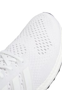 Vit sportskor med ett andningsbart stickat övre lager med ett intrikat mönster, kompletterat med en dämpad sula och snören.