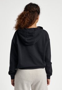 Czarna bluza z kapturem o luźnym kroju, wykonana z miękkiego materiału. Posiada ściągacze przy rękawach i u dołu, brak widocznych logo lub wzorów.