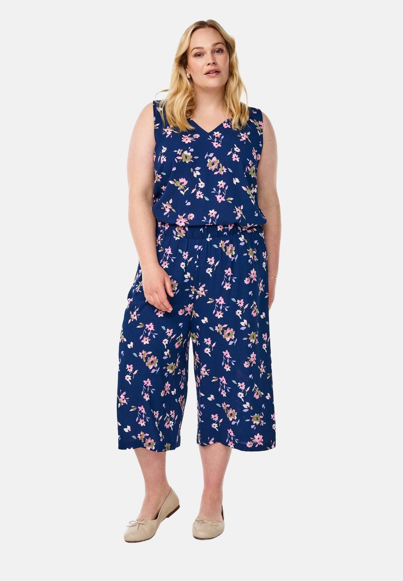 Modra kombinezona z cvetličnim vzorcem, ki vključuje roza in zelene cvetove. V-vrat, brez rokavov in široki krajši hlačnicami. Gladka tekstura materiala.