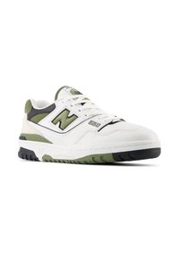 Basket en cuir blanc avec accents verts, présentant un design perforé, un col rembourré et une semelle texturée. Logo New Balance sur le côté.