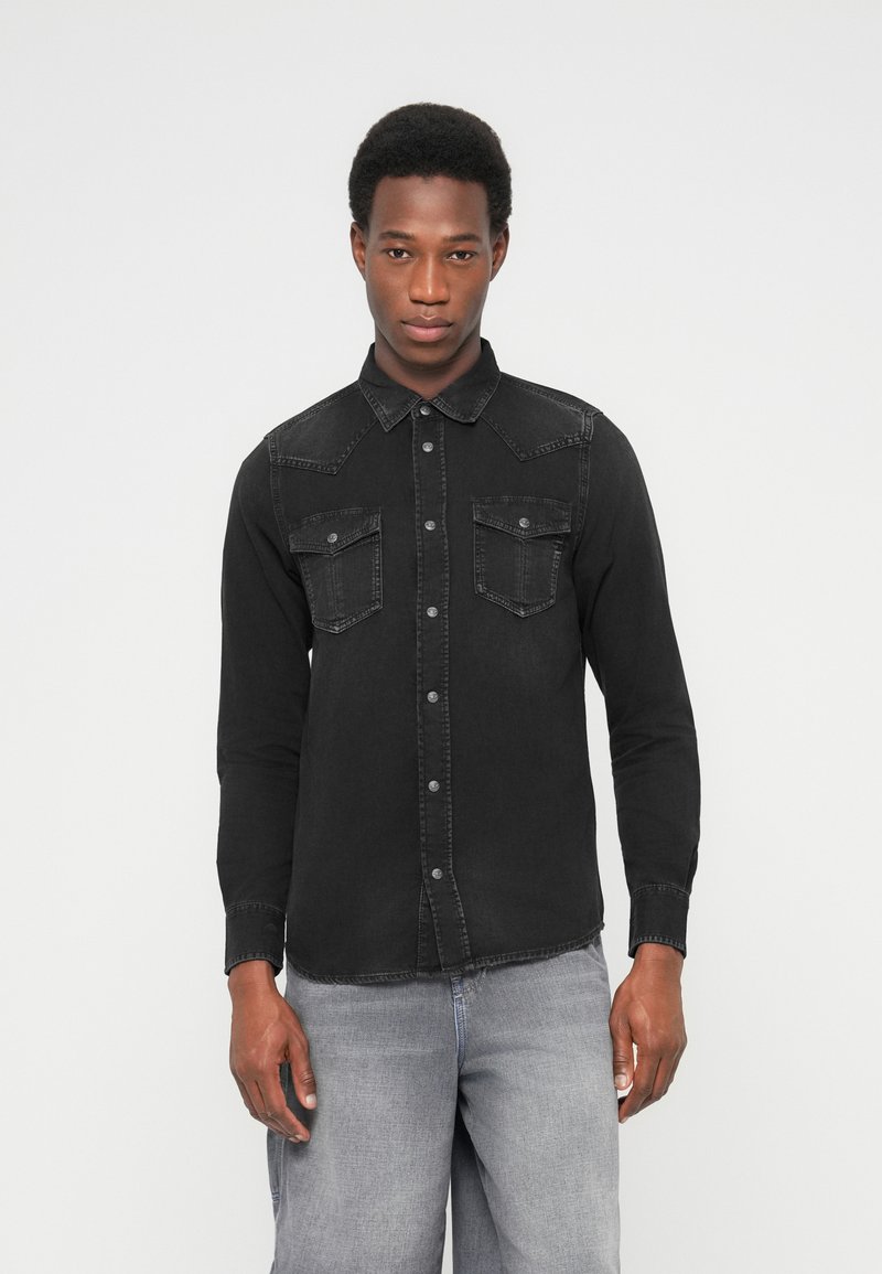 Must teksariidest särk terava kraega, kahe rinnatasku ja nööbitava esiosa. Omaduseks on tikanddetailid ja pikad varrukad.