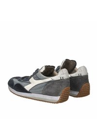 Scarpe da ginnastica con un design in materiali misti, caratterizzate da accenti grigio scuro e grigio chiaro, suede testurizzato e suola in gomma con battistrada geometrico.