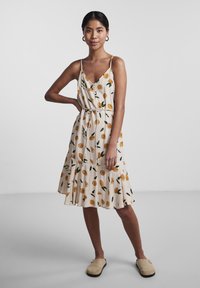 Rochie cu imprimeu floral, cu bretele subțiri, din material bej cu modele de frunze portocalii și verzi răspândite, proiectată cu talie strânsă și tiv evazat.