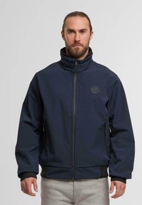 Dunkelblaue Softshell-Jacke mit hohem Kragen, Vorderreißverschluss, zwei Seitentaschen und elastischen Bündchen, hergestellt aus einem strapazierfähigen, strukturierten Stoff.