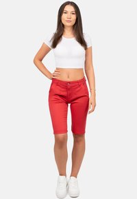 Rode denim bermuda shorts met voorzakken en een licht getailleerd ontwerp. Gecombineerd met een witte crop top en witte sneakers.