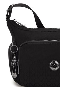 Borsa a spalla nera in nylon con texture geometrica, tasca con zip e accessori in metallo argentato. Presenta un accessorio portachiavi e una tracolla regolabile.
