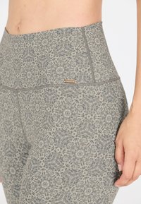 Hoge taille, textuur leggings in een grijs patroon met ingewikkelde ontwerpen. Kenmerkt een subtiele logo-accent op de tailleband.