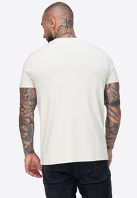 Kratki rukav krem majica s okruglim izrezom, izrađena od mekog pamuka, s glatkom teksturom i minimalnim dizajnom.