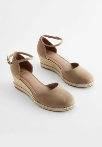Beige espadrilky na klínu s texturovaným semišovým svrškem, kulatou špičkou, kotníkovým páskem a tkaným jutu pokrytým klínem.