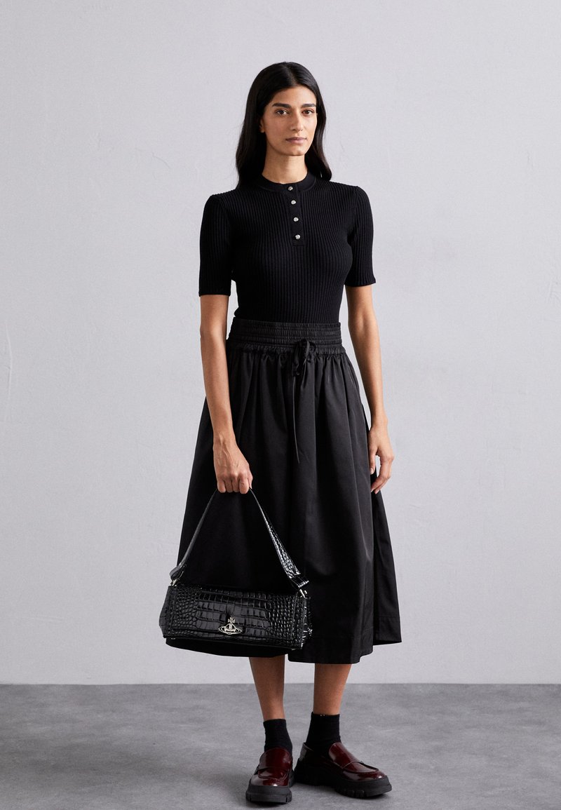 Top preto com riscas e mangas curtas, com detalhe de botões, combinado com uma saia preta de cintura alta e sapatos plataforma brilhantes na cor bordô. Bolsa preta incluída.