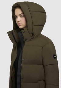 Olive green padded jacket with a detachable hood, front zipper, and snap buttons. Features a logo patch on the left sleeve.