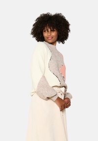 Knit pullover sweater in cream, light brown, and pink with a textured pattern. Features a high neck and relaxed fit with ribbed cuffs.
