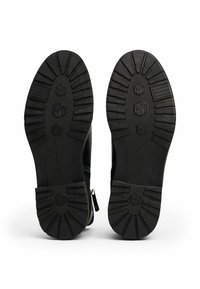 Černé gumové podrážky s hlubokými vzorky. Obsahuje zipové zapínání a strukturovaný povrch. Odolný design vhodný pro různé terény.