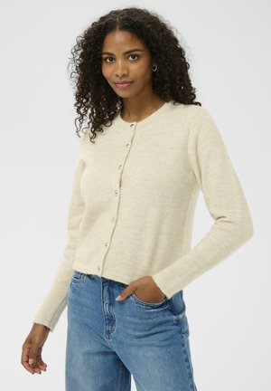 Creme strikket cardigan med rund halsudskæring, knaplukning foran og rib strømpen. Matchende med lyseblå denim jeans.