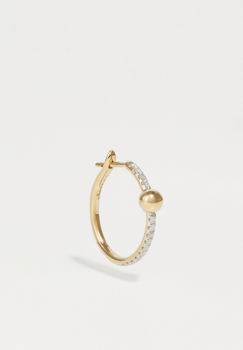 Złota kolczyk w kształcie obręczy z małym akcentem w postaci sfery, ozdobionym rzędem przezroczystych, błyszczących kamieni z przodu. Gładka, wypolerowana powierzchnia.