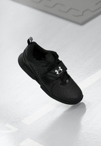 Czarne buty sportowe z perforowanym wzorem, grubą podeszwą i regulowanym paskiem. Zawierają logo z boku oraz teksturowaną pętelkę na pięcie.