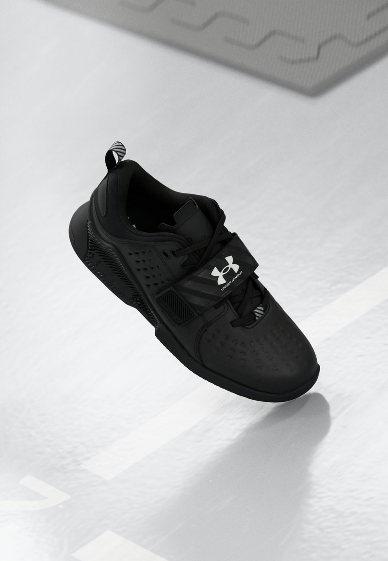 Czarne buty sportowe z perforowanym wzorem, grubą podeszwą i regulowanym paskiem. Zawierają logo z boku oraz teksturowaną pętelkę na pięcie.