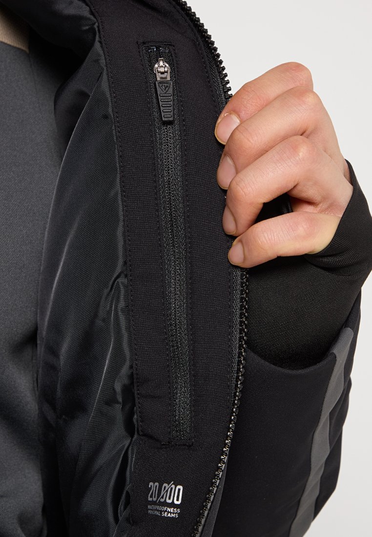 Schwarze wasserfeste Jacke mit glatter Textur, ausgestattet mit einer kurzen Reißverschlusstasche und kontrastierenden grauen Akzentuierungen entlang des Ärmels.