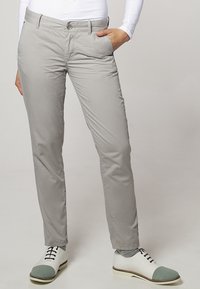 Světle šedé kalhoty z hladkého materiálu, se slim fit střihem, předními kapsami a zapínáním na knoflík. V kombinaci s bílými botami se šedými akcenty.