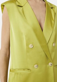 Limonengrünes doppelt geknöpftes Weste mit tiefem V-Ausschnitt, ausgestattet mit hellen Knöpfen und einer glatten Satin-Oberfläche. Mit Fronttaschen.