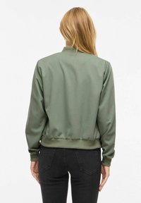 Veste bomber vert olive, en satin lisse, ourlet et poignets côtelés, design simple sans motifs ni accessoires visibles.