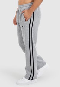 Graue Sweatpants aus weichem Stoff, mit schwarzen Seitestreifen und einem elastischen Bund. Enthält Seitentaschen zur Aufbewahrung.