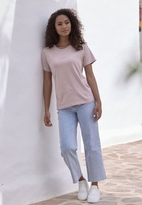 Light pink cotton t-shirt with short sleeves, paired with light blue cropped jeans. White sneakers complete the casual outfit.