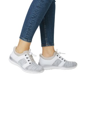 Graue und weiße Sportschuhe mit einem strukturierten Strick-Obermaterial, Schnürsystem und einer glatten Gummisohle, kombiniert mit blauen Jeanshosen.