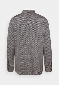 Svart- och vitmönstrad långärmad skjorta med krage som knäpps, med små geometriska former och en rak skärning.