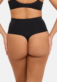 Gain de taille noire taille haute avec un tissu lisse et extensible. Le design sans couture offre une couverture complète et un ajustement confortable. Les accents comprennent une large ceinture.