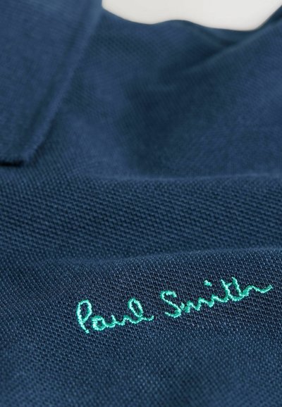 Sötétkék pólóing texturált anyagból, elöl világoszöld hímzett "Paul Smith" logóval.