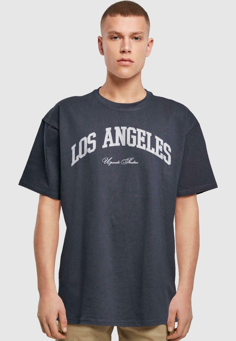 Tumši pelēks pārspīlēts T-krekls ar tekstu "LOS ANGELES" baltā krāsā krūtīs un smalku izliekumu. Brīva piegriezuma, īsas piedurknes.