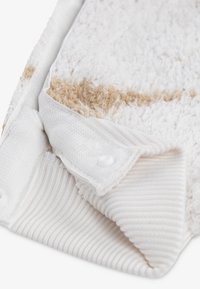 Weißes Handtuch mit strukturiertem, flauschigem Material und einem hellbraunen Streifen. Verfügt über einen gerippten weißen Rand und einen Druckknopfverschluss. Weiches Material.