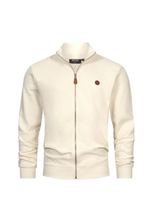 Cream-colored zip-up jacket made of ribbed material. Features a stand-up collar, slim fit, and a small circular brown logo on the chest.