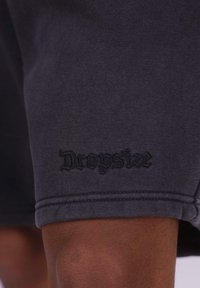 Sorte sportsshorts med en blød tekstur, der har et broderet "Drophsize" logo på kanten. Simpelt design og længde til midt på låret.
