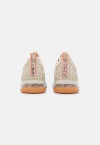 Beige athletic shoes with a translucent sole, featuring textured fabric and a pink accent on the pull tab labeled "FASHLETICS."