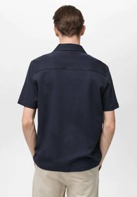 Marineblauwe korthalshemd met een rechte rugwijs en strakke lijnen. Katoenmengsel met een gladde textuur, eenvoudig en modern ontwerp.