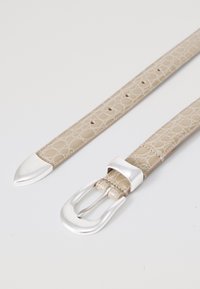 Cinturón de piel beige con textura de cocodrilo, que presenta una hebilla y punta de metal plateado, diseñado con agujeros de ajuste espaciados de manera uniforme.