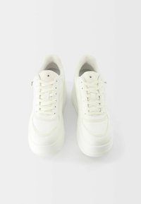 Sneakers bianchi in materiale di pelle liscia, punta tondeggiante, lacci piatti e suola testurizzata. Design minimalista con dettagli di cucitura discreti.