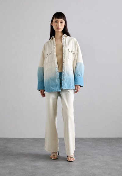 Jachetă din denim cu un gradient de la crem la albastru, croială supradimensionată, două buzunare frontale, asortată cu pantaloni largi crem și sandale cu barete.
